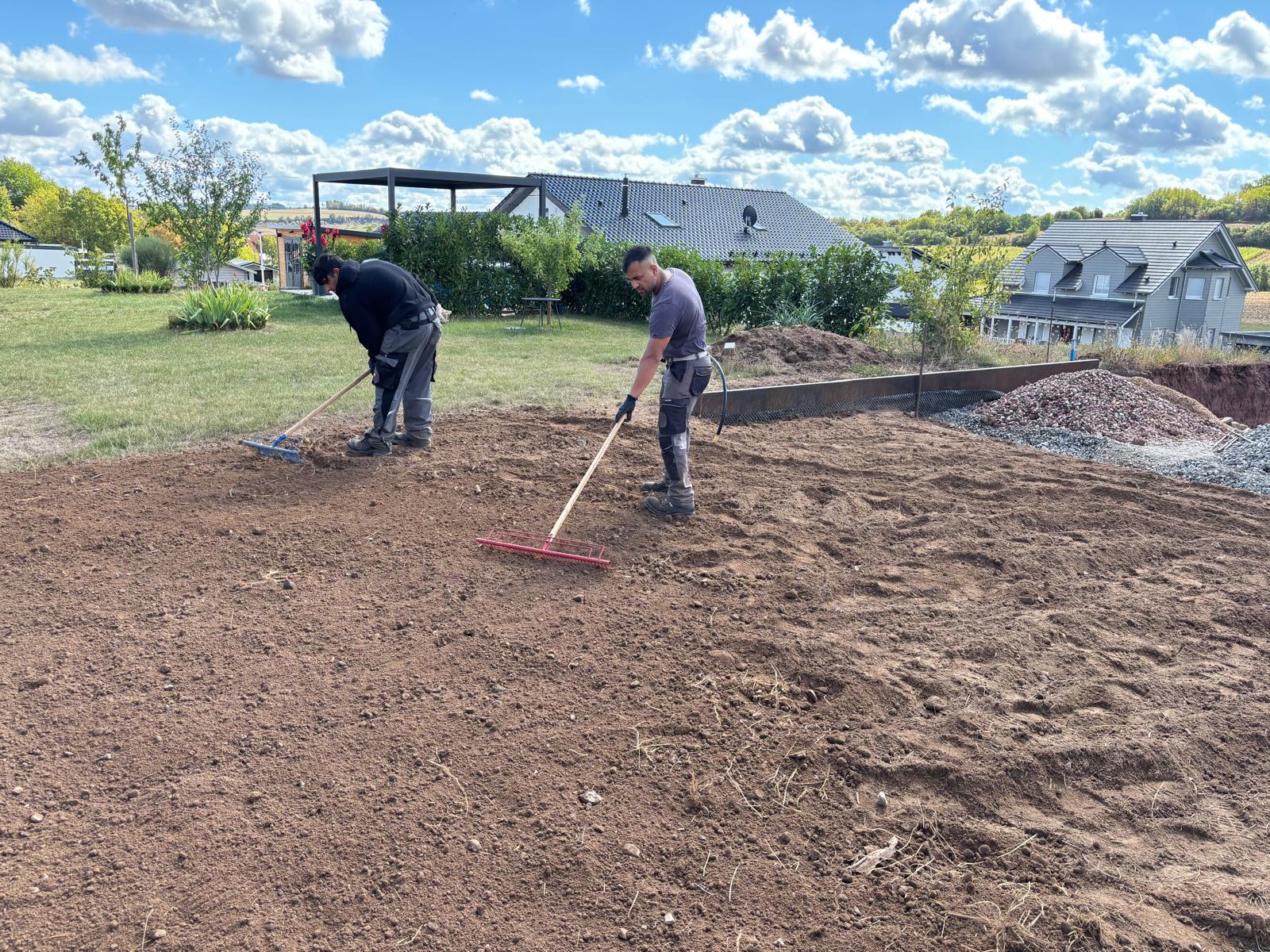 Mitarbeiter von Watan Gartenservice ziehen den Boden einer Gartenfläche in Buchen ab
